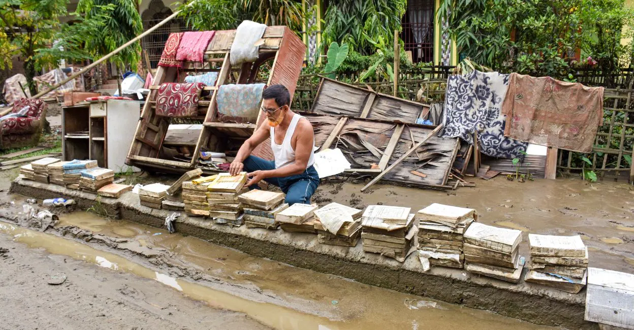 An advocate dries flood-damaged legal books and documents outside his residence after floodwaters receded in Santak of Sivasagar district in Assam on August 3. Photo: PTI