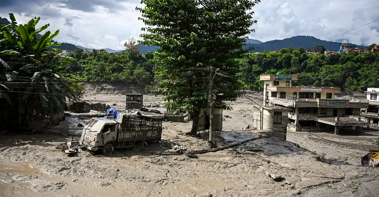 A truck and structures stand partially submerged in a thick layer of mud and debris following flash floods at Beni Ghat area, in Dhading of Nepal. Photo: PTI